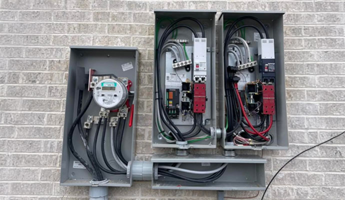 Electrical meter and breaker panels mounted on a brick wall