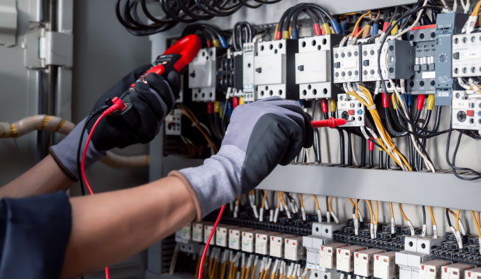 Electrician testing industrial control panel