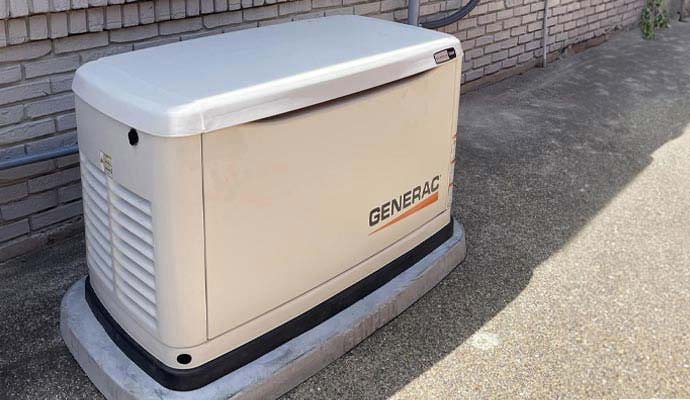 Generac standby generator installed along brick wall